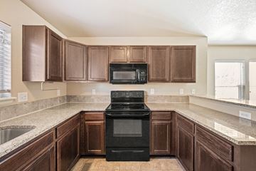 Castle Rock apartment for rent - A kitchen with brown cabinets and a black stove top oven.